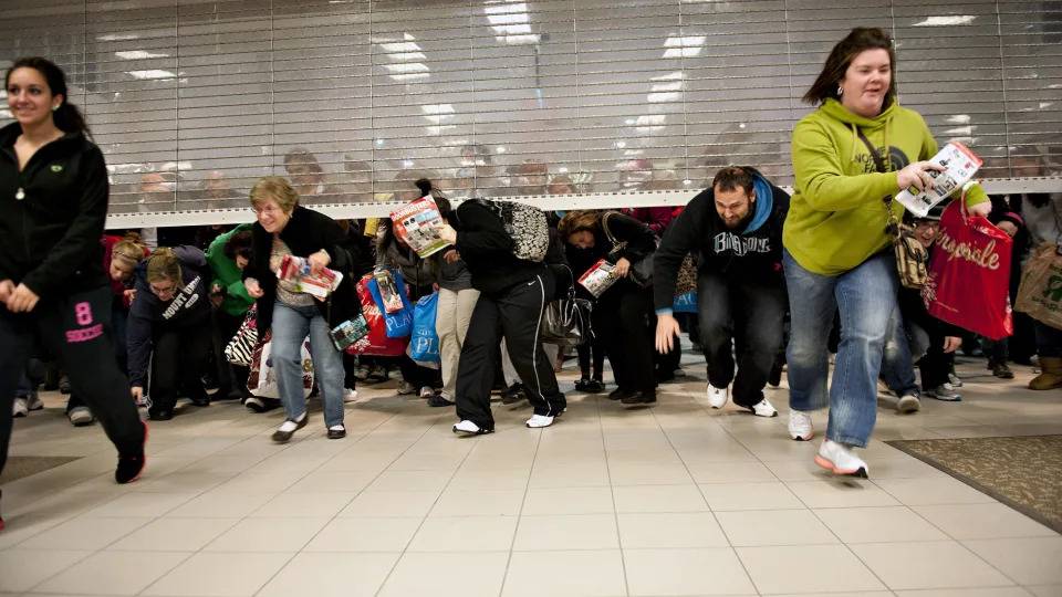 صورة تظهر متسوقون يمروا من أسفل باب أحد المتاجر في تدافع