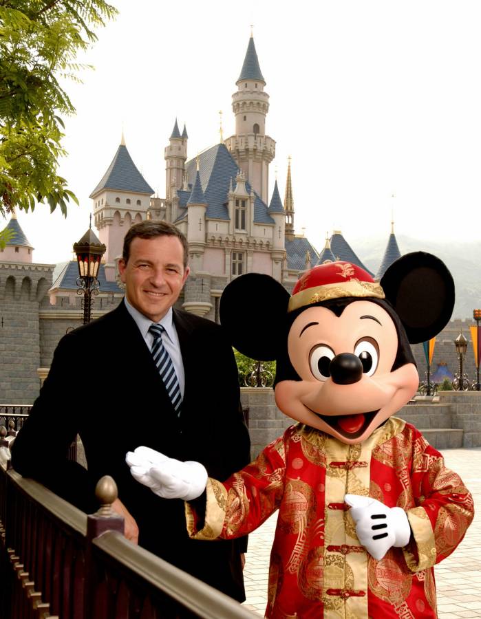 بوب إيغر يقف إلى جانب ميكي ماوس أمام قلعة الجمال النائم في حديثة ديزني لاند (رويترز)